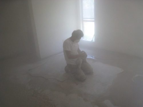 Construction worker kneels in an extra dust filled room